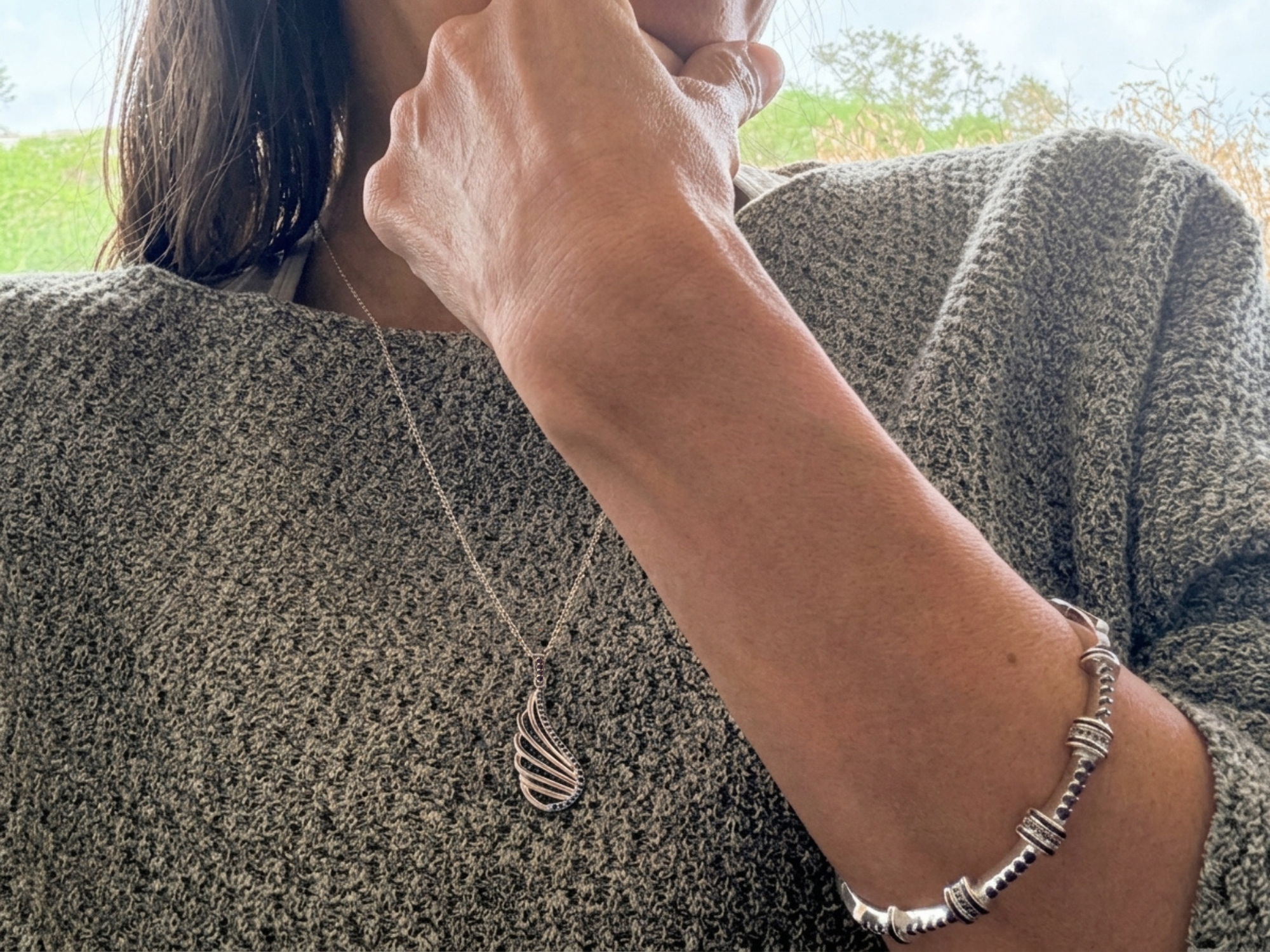 Silver pendant necklace and bangle bracelets styled for everyday wear.
